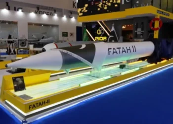 A large, white missile labeled "FATAH-II" is displayed on a yellow platform at an exhibition